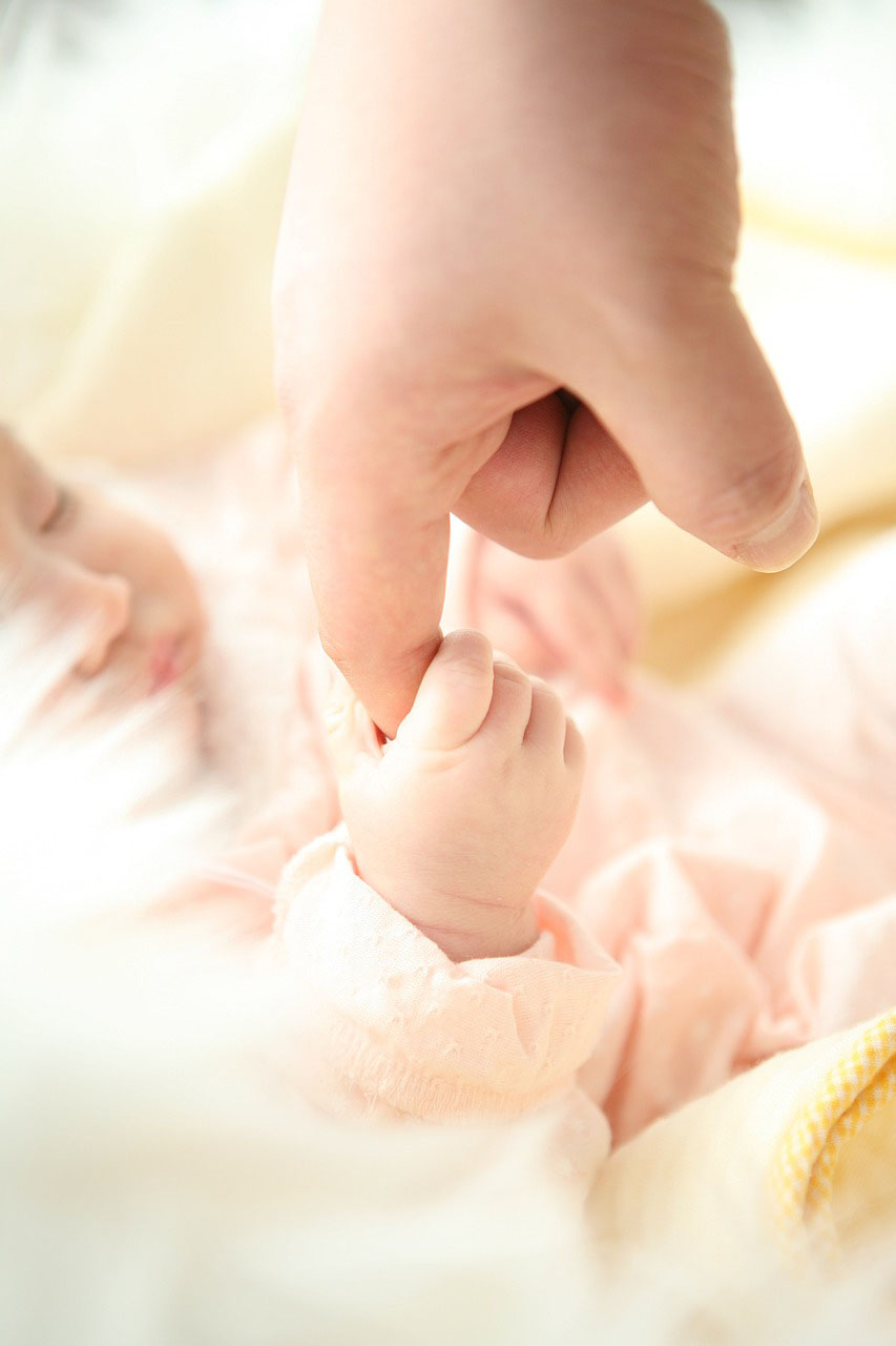 Baby som håller förälder i pekfingret